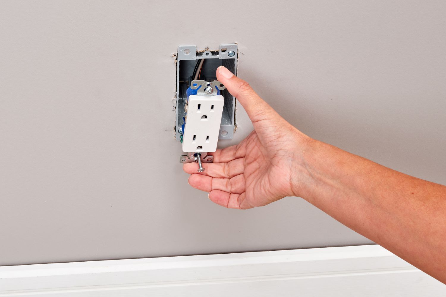 Hand reaching to remove an outlet from the drywall